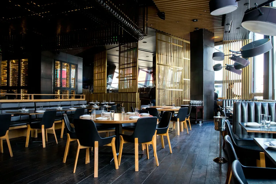 Sala de un restaurante con mesas de madera y luz cálida